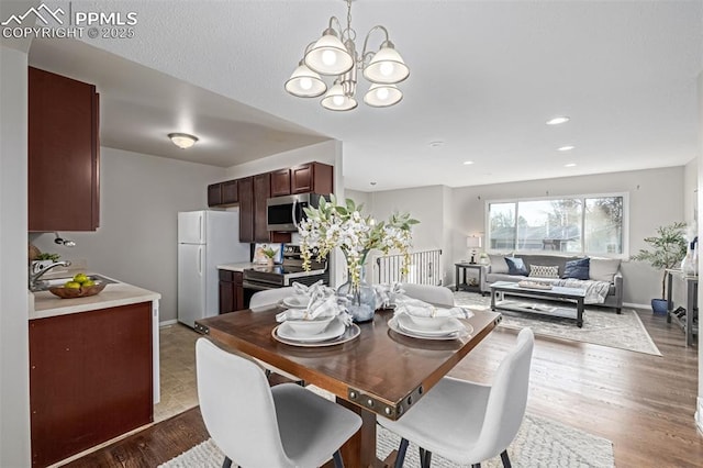 dining area with sink, hardwood / wood-style flooring, and a chandelier