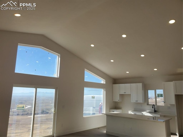 kitchen with white cabinetry, sink, high vaulted ceiling, and a center island