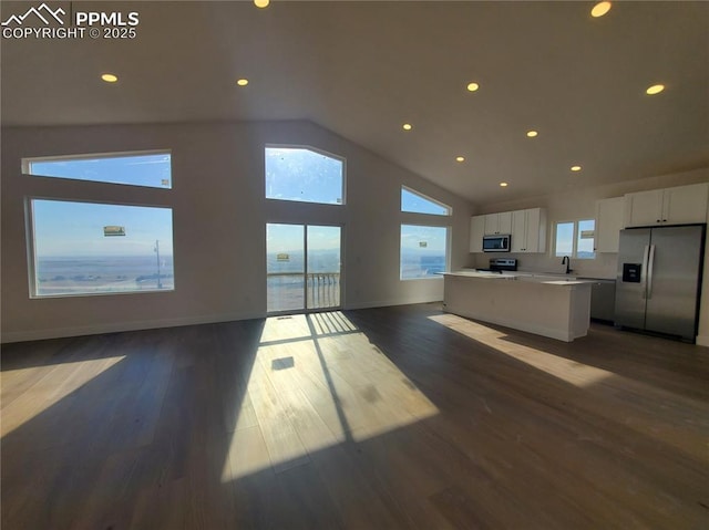 kitchen featuring a kitchen island, white cabinets, open floor plan, appliances with stainless steel finishes, and dark wood-style floors