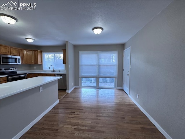 kitchen with dark wood-type flooring, stainless steel appliances, sink, and a textured ceiling