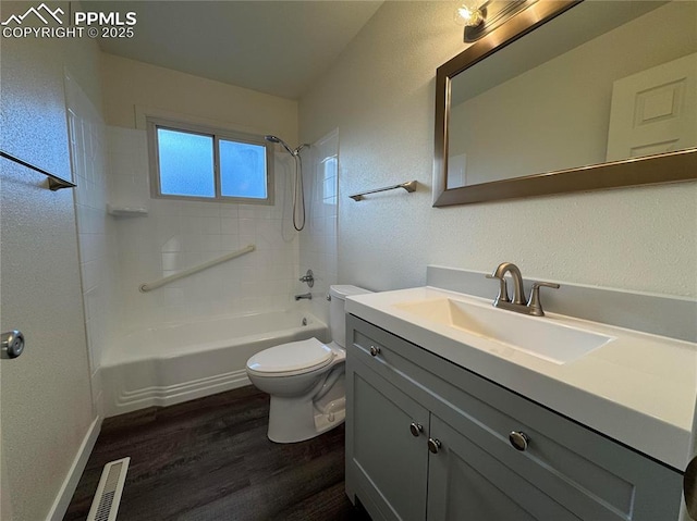 full bathroom with hardwood / wood-style flooring, tiled shower / bath, vanity, and toilet