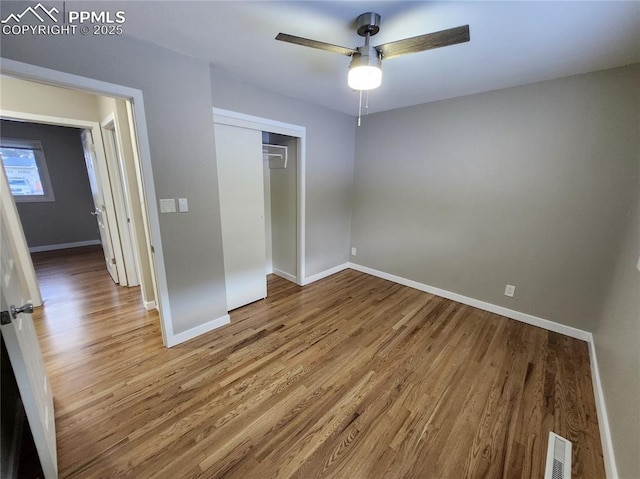 unfurnished bedroom with ceiling fan, wood-type flooring, and a closet