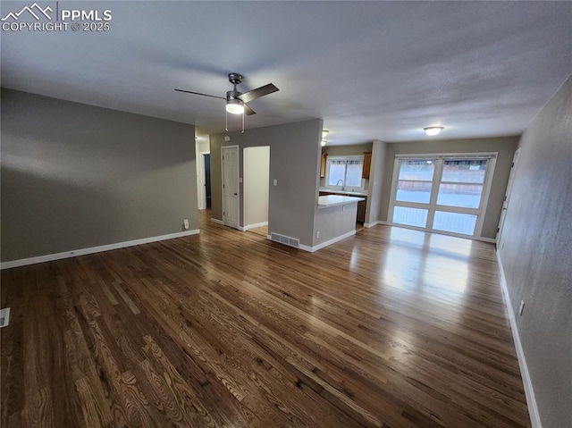 unfurnished living room featuring dark wood-type flooring, sink, and ceiling fan