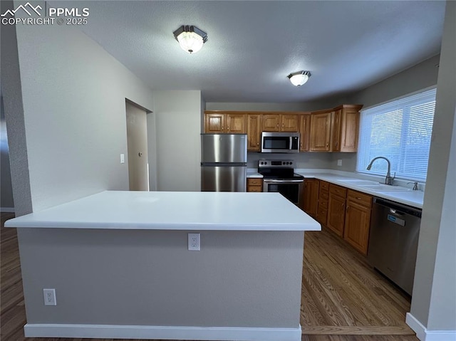 kitchen with sink, hardwood / wood-style flooring, stainless steel appliances, and a kitchen island