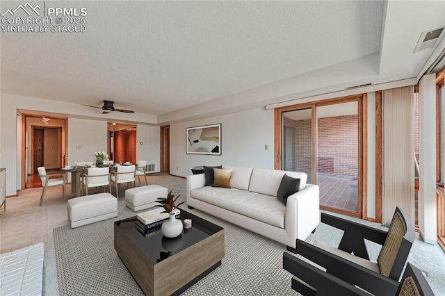 living room with ceiling fan and a textured ceiling