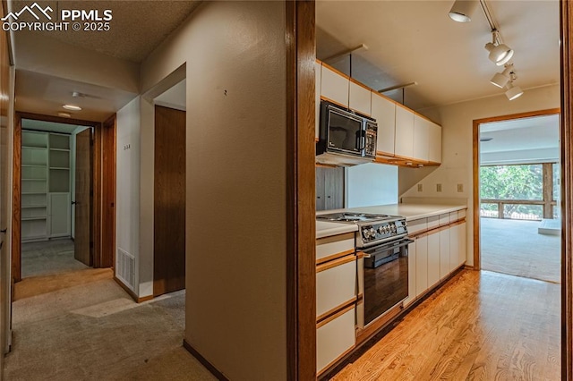 kitchen featuring light hardwood / wood-style flooring, track lighting, white cabinets, and stainless steel gas stove