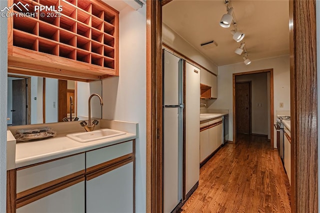 kitchen featuring sink, stainless steel range, refrigerator, and light hardwood / wood-style flooring