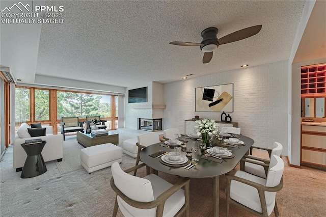 dining room featuring ceiling fan, brick wall, light carpet, and a textured ceiling