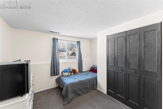 bedroom with a closet, carpet, and a textured ceiling