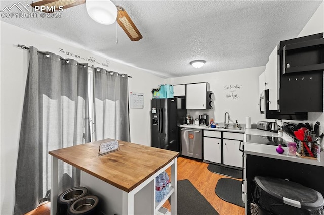 kitchen featuring sink, dishwasher, white cabinetry, light hardwood / wood-style floors, and black fridge