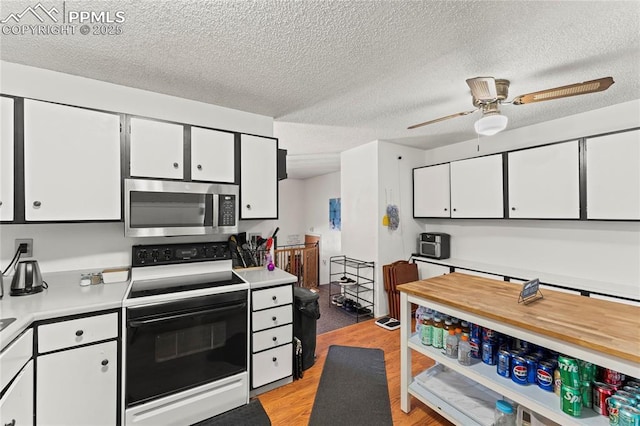 kitchen featuring white cabinetry, electric range oven, light hardwood / wood-style flooring, and a textured ceiling