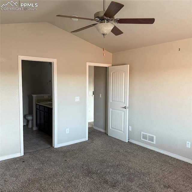 unfurnished bedroom featuring dark colored carpet, vaulted ceiling, connected bathroom, and ceiling fan