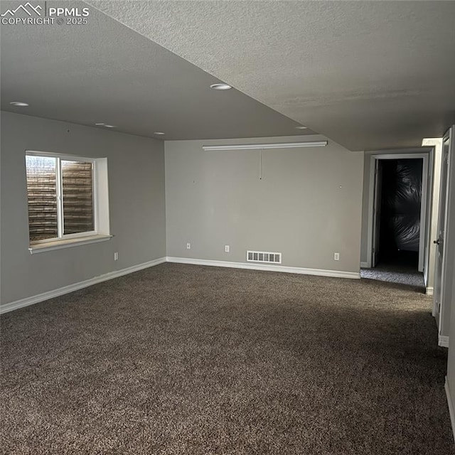 carpeted empty room featuring a textured ceiling