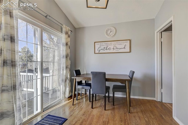 dining area featuring hardwood / wood-style flooring and vaulted ceiling