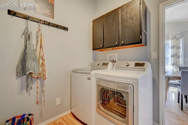 laundry room featuring cabinets, washing machine and clothes dryer, and light wood-type flooring