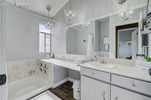 bathroom with vanity, hardwood / wood-style floors, an inviting chandelier, and a tub to relax in