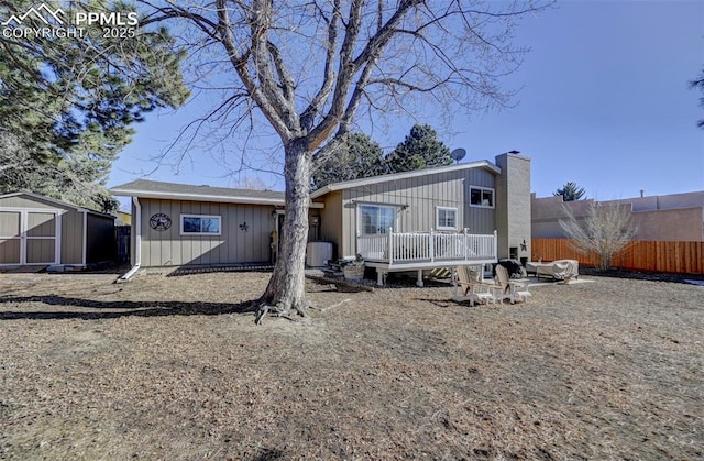 rear view of house with a wooden deck and a storage unit