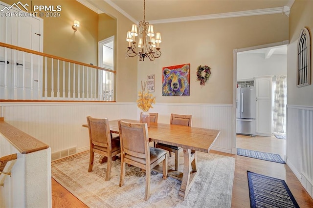 dining space with an inviting chandelier, crown molding, a wealth of natural light, and light hardwood / wood-style floors