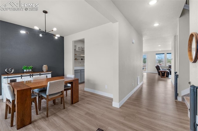 dining space with an inviting chandelier, light hardwood / wood-style floors, and built in shelves