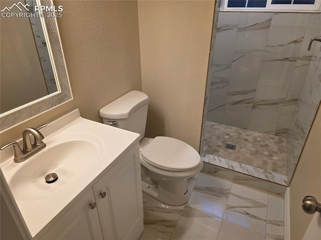 bathroom with vanity, toilet, and tiled shower