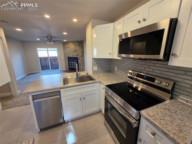 kitchen featuring sink, appliances with stainless steel finishes, white cabinets, decorative backsplash, and kitchen peninsula