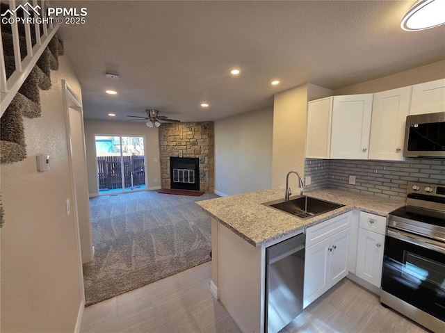 kitchen with light stone counters, stainless steel appliances, sink, and white cabinets