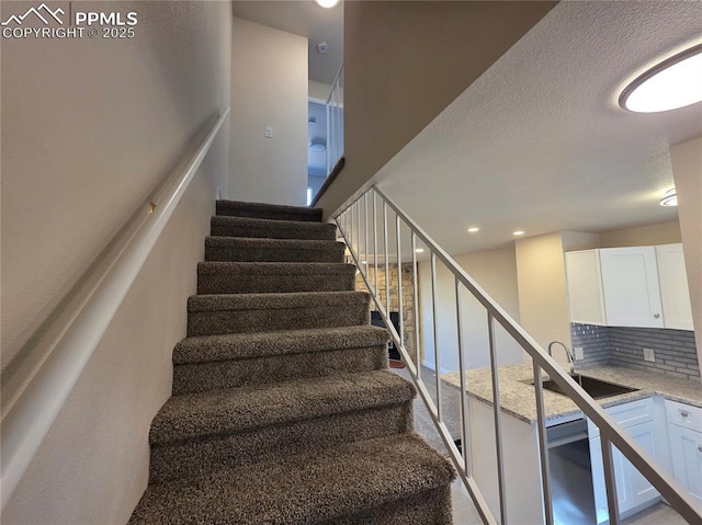 staircase featuring sink and a textured ceiling