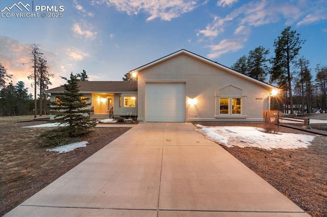 single story home featuring stucco siding, concrete driveway, and an attached garage