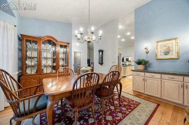 dining room featuring a notable chandelier, light wood-style flooring, and a towering ceiling