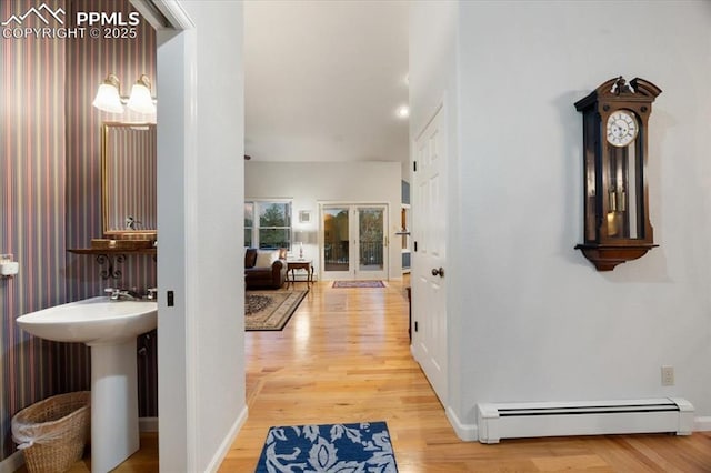 corridor with wood finished floors, baseboards, and a baseboard radiator