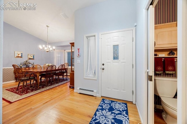 entrance foyer featuring light wood-type flooring, a baseboard radiator, lofted ceiling, and a notable chandelier