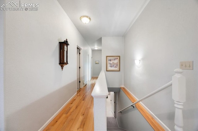 hall with an upstairs landing, light wood-style floors, and baseboards