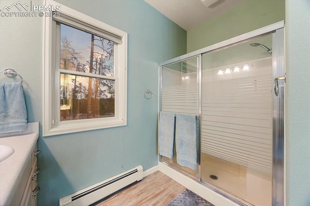 full bathroom with baseboards, baseboard heating, a stall shower, wood finished floors, and vanity