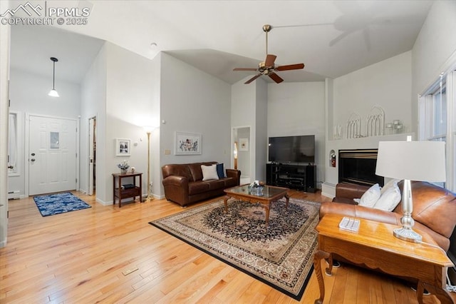 living room featuring high vaulted ceiling, a baseboard heating unit, light wood-style floors, baseboards, and ceiling fan