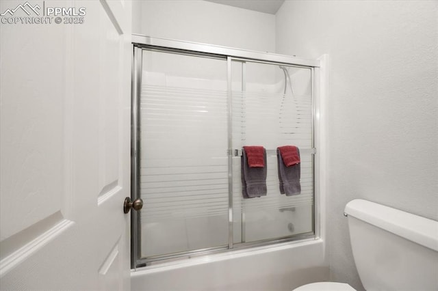 full bath featuring combined bath / shower with glass door and toilet