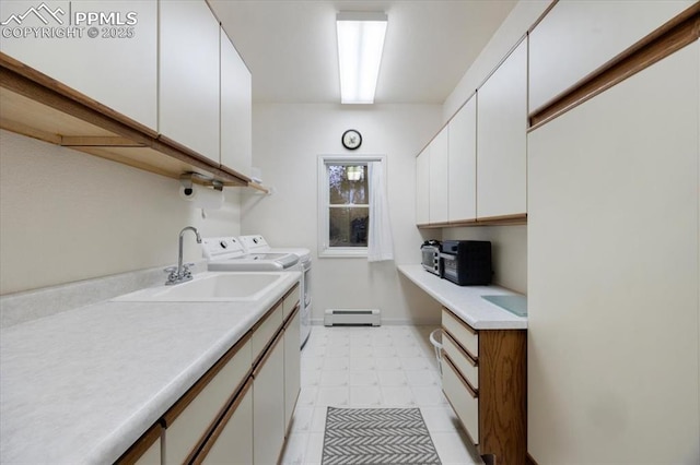 laundry room with a baseboard heating unit, light floors, separate washer and dryer, cabinet space, and a sink