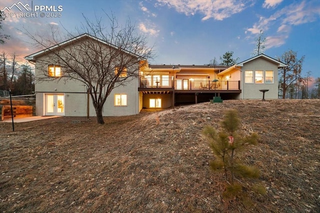 rear view of house with stucco siding, french doors, and a wooden deck