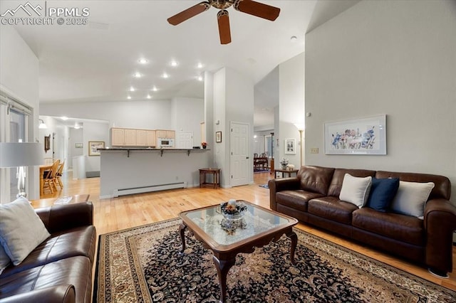 living area with a baseboard radiator, light wood-style floors, ceiling fan, and high vaulted ceiling