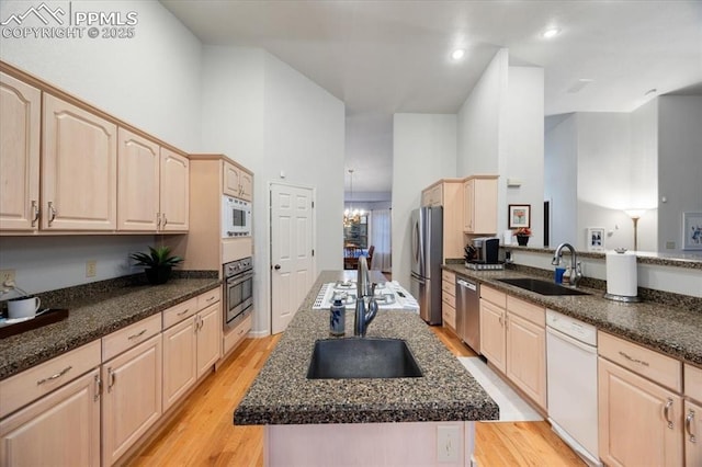 kitchen with an island with sink, light brown cabinets, appliances with stainless steel finishes, and a sink