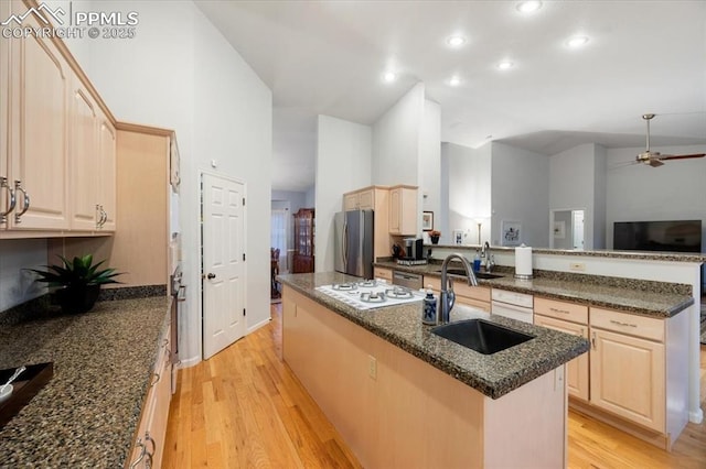 kitchen featuring light brown cabinets, a kitchen island with sink, freestanding refrigerator, a sink, and light wood-style floors