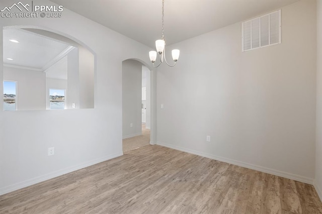 empty room featuring a chandelier and light hardwood / wood-style floors