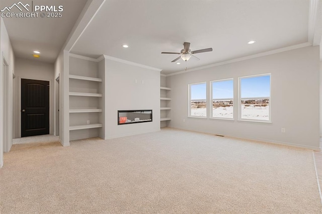 unfurnished living room featuring built in shelves, light colored carpet, ornamental molding, and ceiling fan