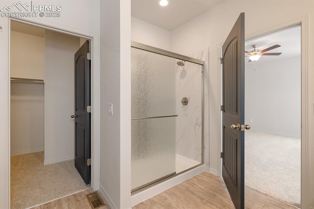 bathroom with ceiling fan, wood-type flooring, and an enclosed shower