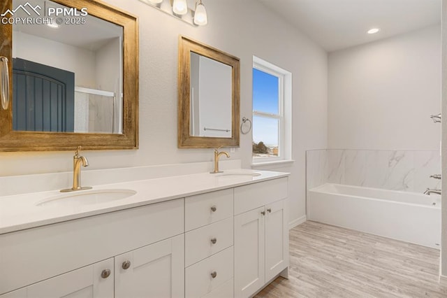 bathroom featuring vanity, a bath, and wood-type flooring