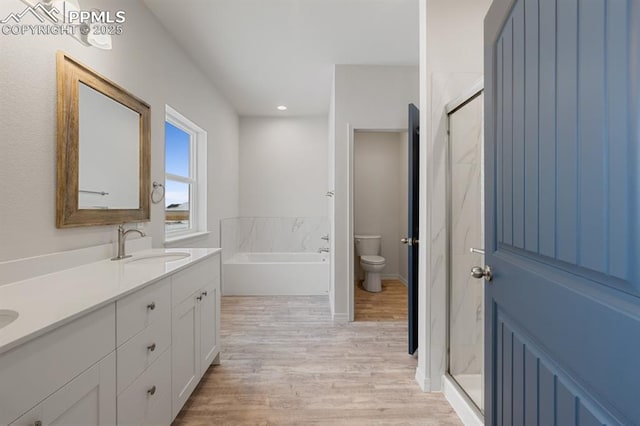 full bathroom with hardwood / wood-style flooring, vanity, toilet, and separate shower and tub