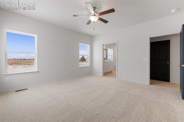 unfurnished bedroom with ensuite bathroom, light colored carpet, and ceiling fan