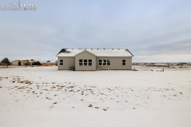 snow covered rear of property featuring central AC unit