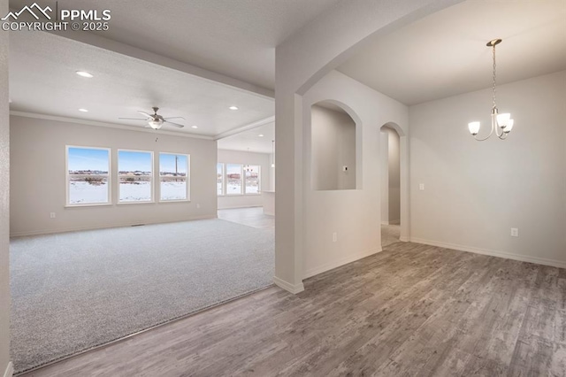 unfurnished room featuring hardwood / wood-style flooring, ornamental molding, and ceiling fan with notable chandelier