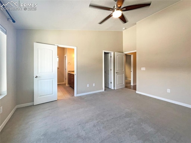 unfurnished bedroom featuring vaulted ceiling, light colored carpet, ceiling fan, and ensuite bathroom