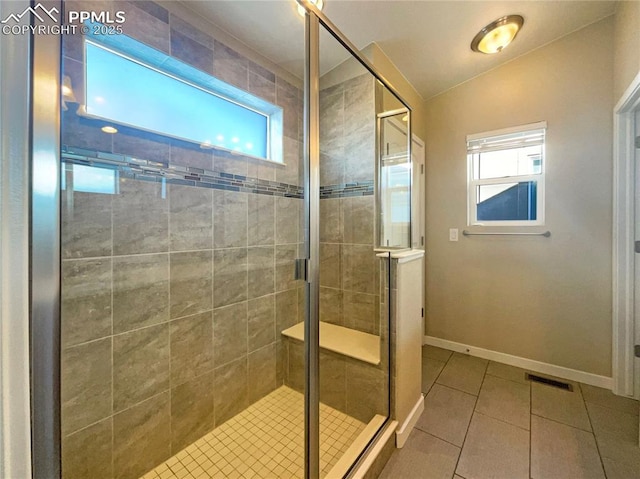 bathroom with tile patterned flooring, vaulted ceiling, a wealth of natural light, and walk in shower